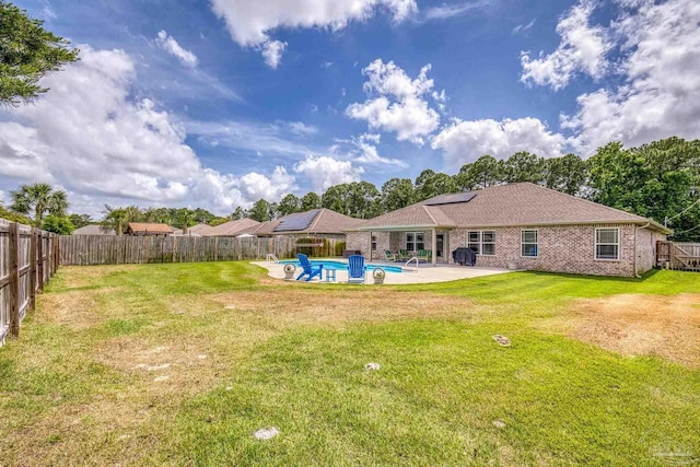 rear view of property with roof mounted solar panels, a patio, and brick siding
