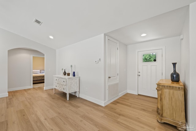 foyer with arched walkways, light wood-style flooring, baseboards, and recessed lighting