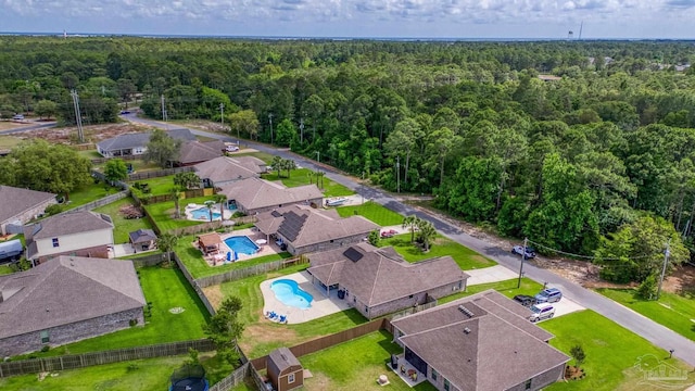 aerial perspective of suburban area featuring a heavily wooded area and a pool area