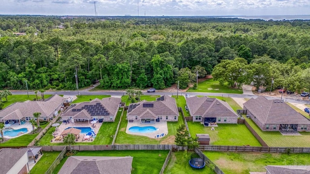 aerial view of residential area featuring a heavily wooded area and a pool area