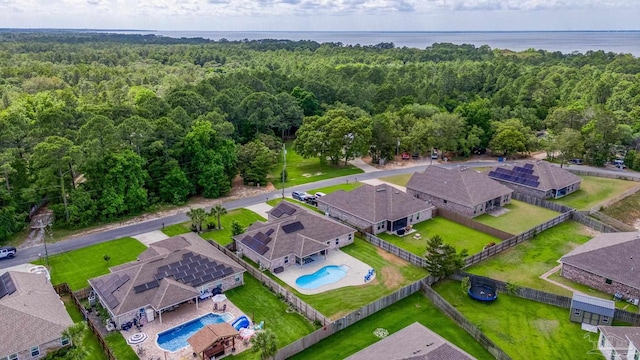 aerial view of residential area featuring a pool and a heavily wooded area