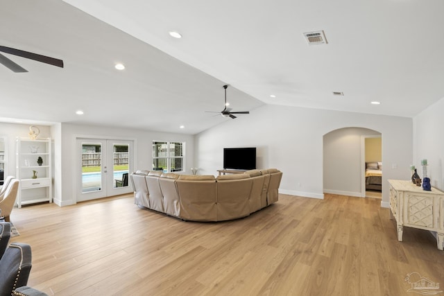 living area with ceiling fan, arched walkways, light wood-type flooring, baseboards, and lofted ceiling