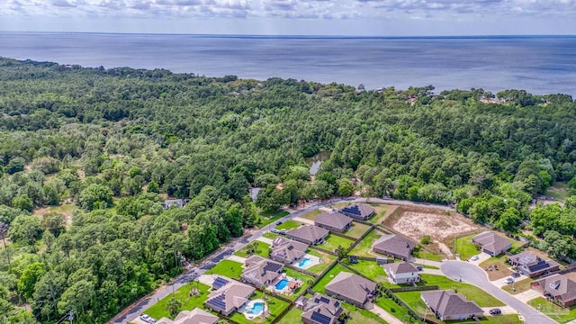 aerial view of property's location featuring a forest, a large body of water, and nearby suburban area
