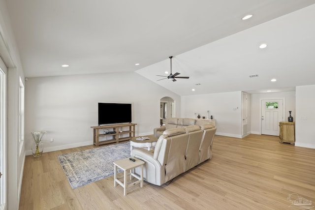 living area featuring arched walkways, ceiling fan, vaulted ceiling, baseboards, and light wood-style floors