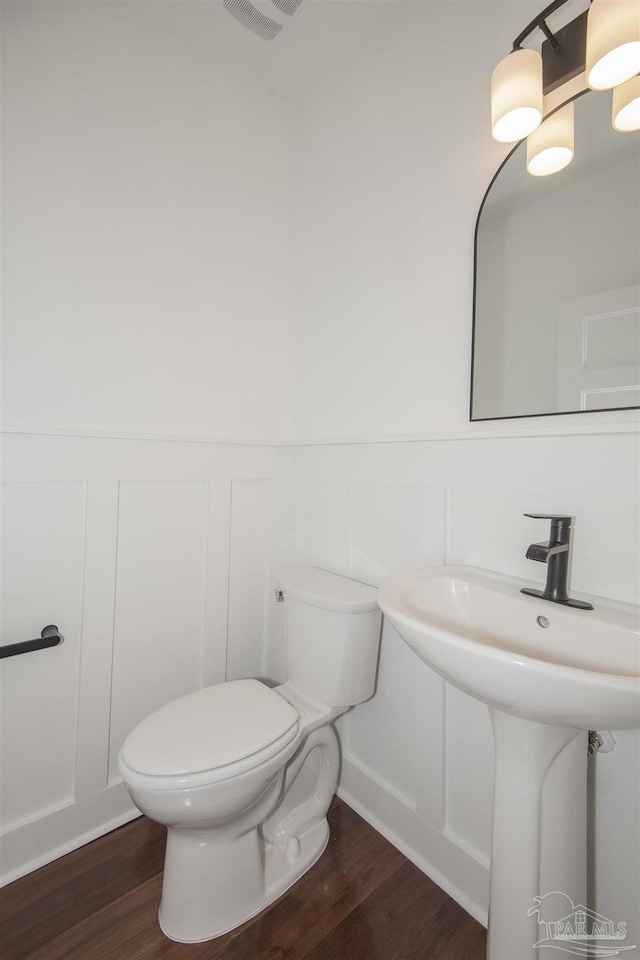 502 W Gregory St, Pensacola, FL 32502 - bathroom with a wainscoted wall, toilet, wood finished floors, and a decorative wall