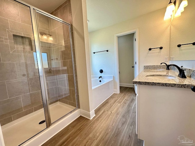 bathroom featuring double vanity, shower with separate bathtub, and hardwood / wood-style floors