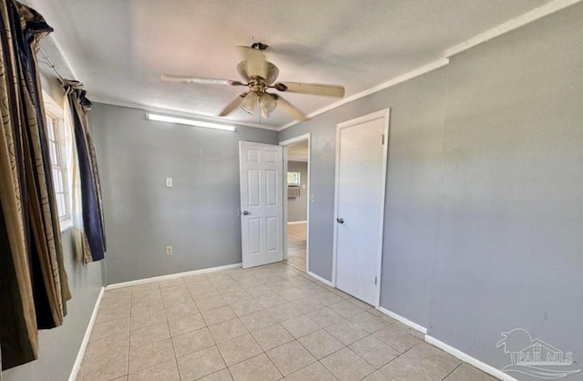 unfurnished bedroom featuring ceiling fan, crown molding, and light tile patterned floors