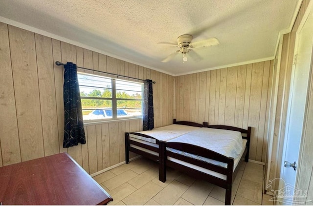 bedroom featuring ceiling fan, a textured ceiling, and wood walls