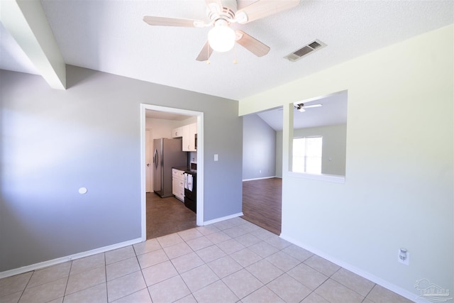 spare room featuring a textured ceiling, ceiling fan, and light tile patterned floors