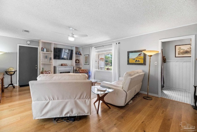 living room with a textured ceiling, light wood finished floors, and ceiling fan