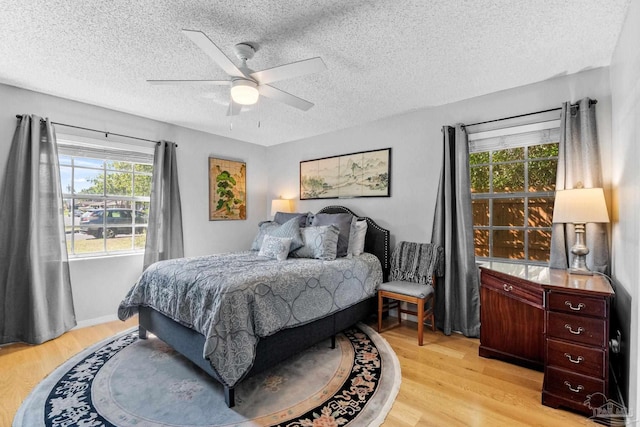 bedroom featuring light wood-style flooring, a ceiling fan, and a textured ceiling