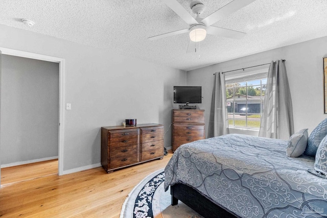 bedroom with baseboards, light wood-style floors, and a textured ceiling