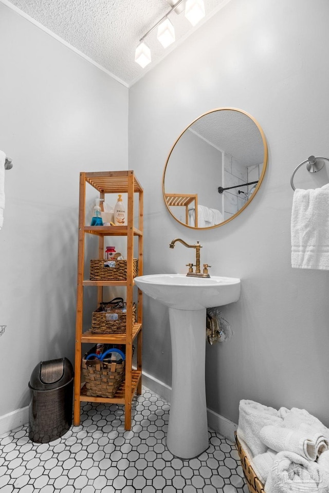 bathroom with a sink, a textured ceiling, baseboards, and crown molding