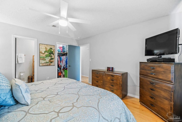 bedroom featuring a closet, a spacious closet, light wood-style flooring, a textured ceiling, and visible vents