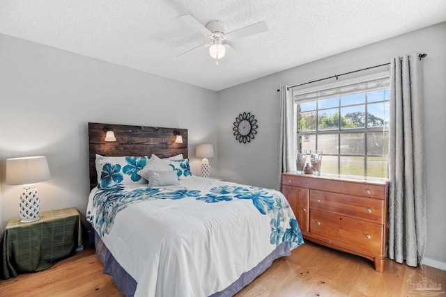 bedroom with a textured ceiling, wood finished floors, and ceiling fan
