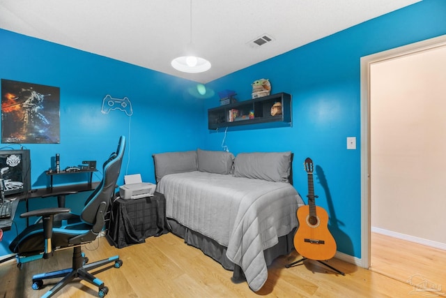 bedroom with visible vents, baseboards, and wood finished floors