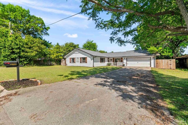ranch-style home with an attached garage, driveway, a front yard, and fence