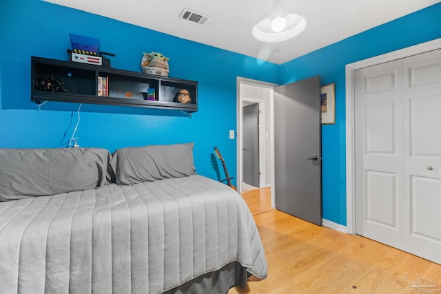 bedroom featuring visible vents, baseboards, a closet, and wood finished floors