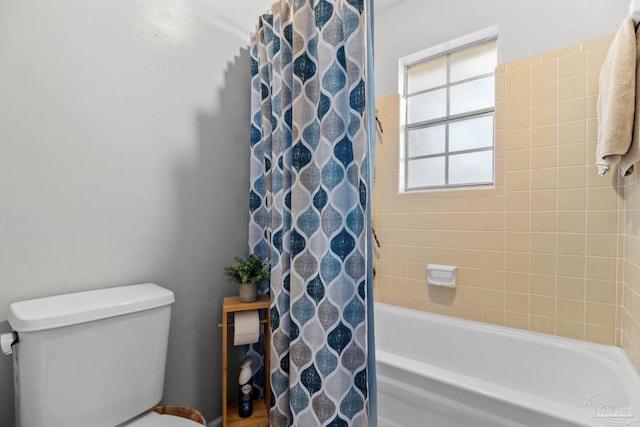 bathroom featuring toilet and shower / bath combination with curtain