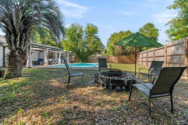 view of yard featuring a fenced in pool, a fire pit, a fenced backyard, and a pergola