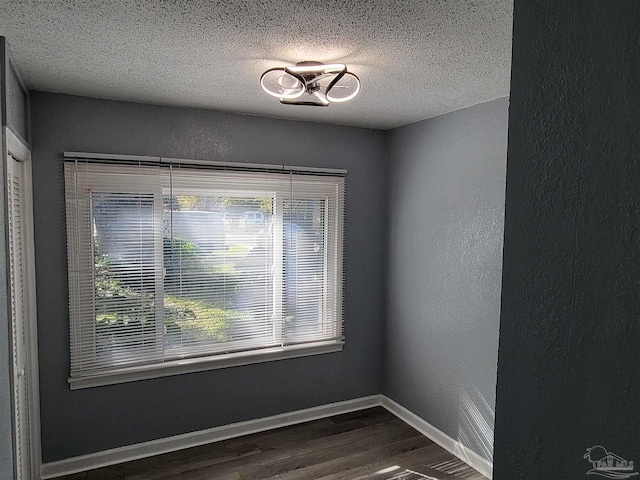 spare room featuring a textured ceiling and dark wood-type flooring