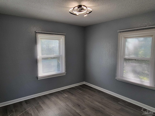 empty room featuring a textured ceiling and dark hardwood / wood-style flooring