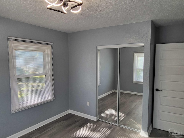 unfurnished bedroom featuring multiple windows, dark hardwood / wood-style flooring, and a closet