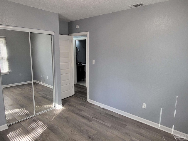 unfurnished bedroom with dark hardwood / wood-style flooring, a closet, and a textured ceiling