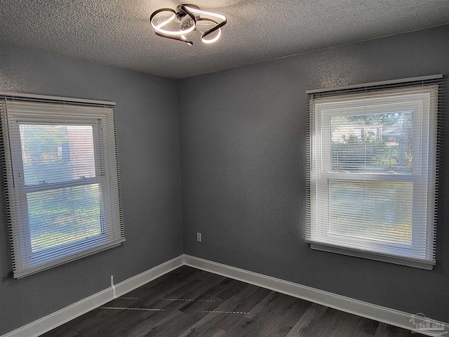 unfurnished room with plenty of natural light, dark hardwood / wood-style flooring, and a textured ceiling