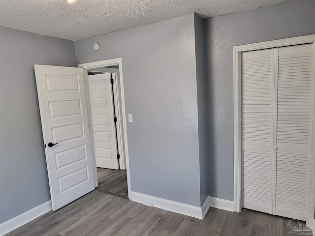 unfurnished bedroom with hardwood / wood-style floors, a textured ceiling, and a closet