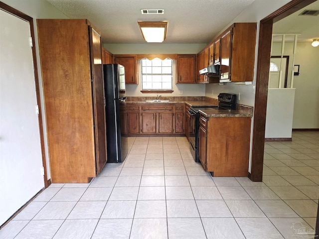 1900 W Kingsfield Rd, Cantonment, FL 32533 - kitchen featuring black appliances, dark countertops, brown cabinets, light tile patterned floors, and under cabinet range hood