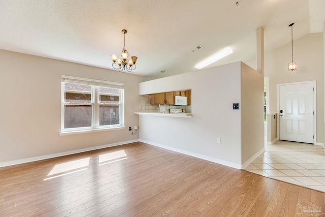 3881 Windsor Castle Blvd, Milton, FL 32583 - unfurnished living room with a chandelier, light wood-style flooring, vaulted ceiling, and baseboards