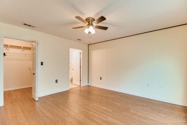 3881 Windsor Castle Blvd, Milton, FL 32583 - unfurnished bedroom featuring light wood-style flooring, a walk in closet, baseboards, and a ceiling fan