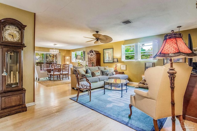 living room featuring ceiling fan with notable chandelier and light hardwood / wood-style flooring