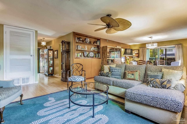 living room with ceiling fan with notable chandelier and light wood-type flooring