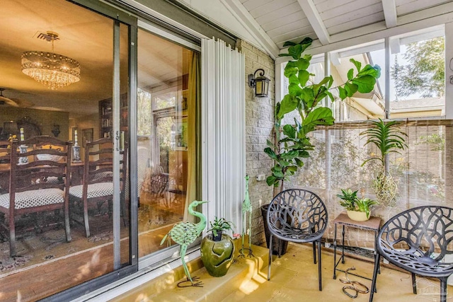 sunroom with vaulted ceiling with beams and an inviting chandelier