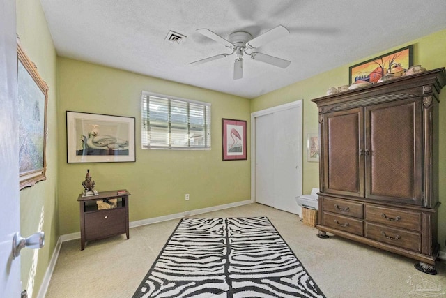 bedroom with light carpet, a textured ceiling, and ceiling fan