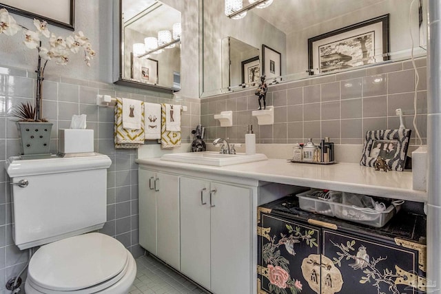 bathroom featuring tile patterned flooring, vanity, toilet, and tile walls