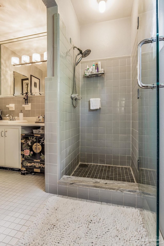 bathroom with an enclosed shower, vanity, tile patterned floors, and tile walls