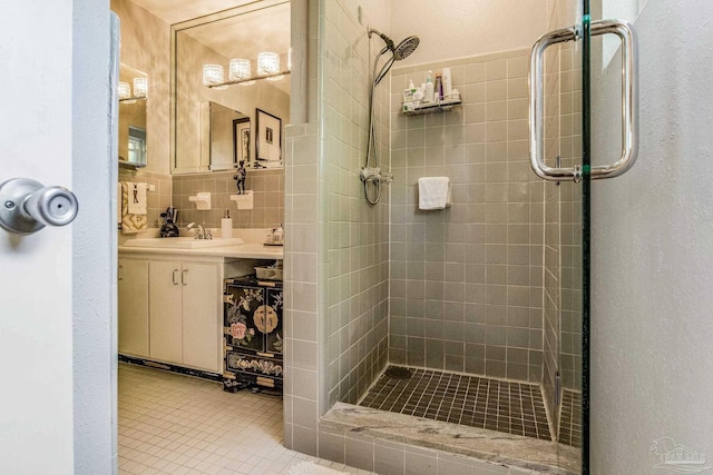 bathroom featuring vanity, tile patterned floors, walk in shower, tile walls, and tasteful backsplash