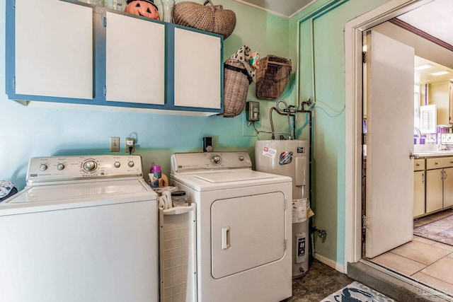 laundry room with washer and clothes dryer, cabinets, dark tile patterned flooring, crown molding, and water heater