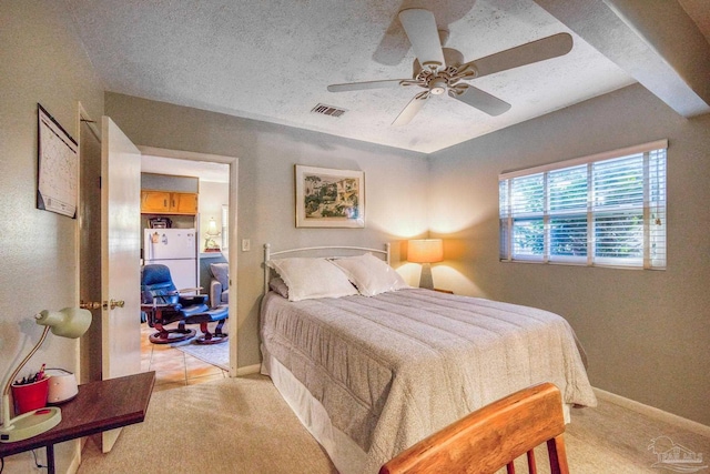 carpeted bedroom featuring ceiling fan, white fridge, and a textured ceiling