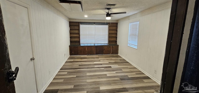 empty room featuring attic access, a textured ceiling, visible vents, and wood finished floors