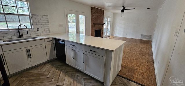 kitchen with a peninsula, a sink, black dishwasher, light countertops, and decorative backsplash