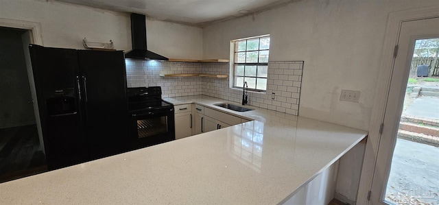 kitchen with open shelves, backsplash, a sink, wall chimney range hood, and black appliances