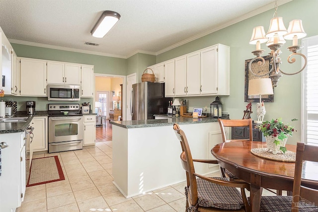 kitchen featuring white cabinetry, appliances with stainless steel finishes, an inviting chandelier, and decorative light fixtures