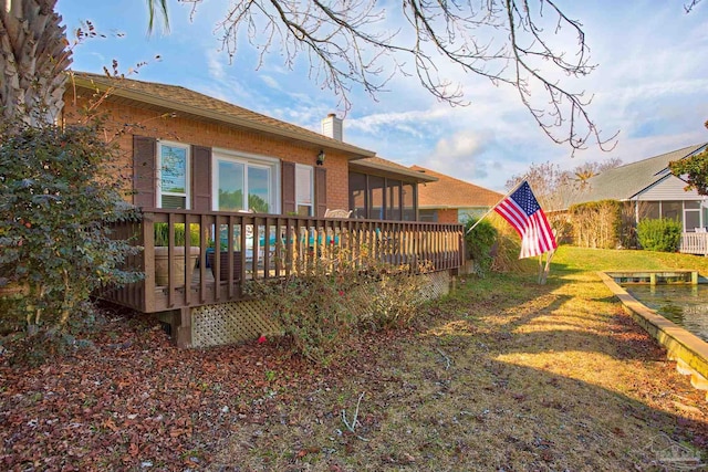 rear view of house featuring a wooden deck and a lawn