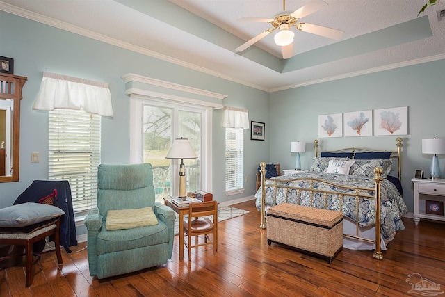 bedroom with ornamental molding, a tray ceiling, and dark hardwood / wood-style flooring