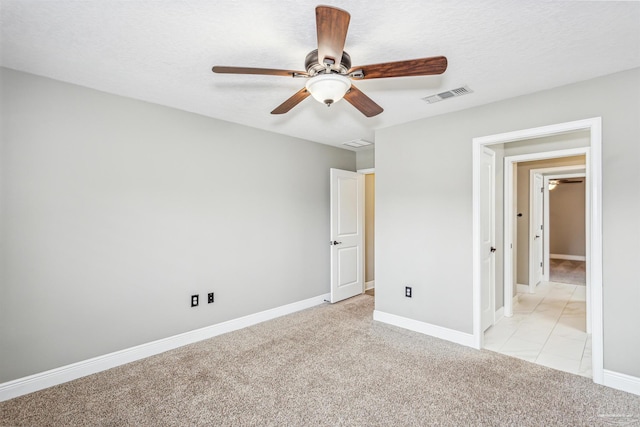 unfurnished bedroom with a textured ceiling, light colored carpet, and ceiling fan