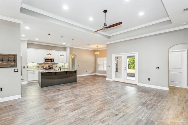 kitchen featuring a center island with sink, white cabinets, light hardwood / wood-style flooring, light stone counters, and stainless steel appliances